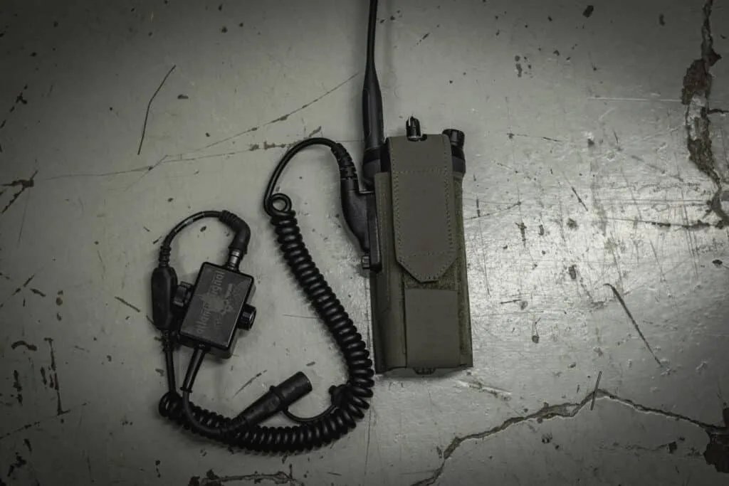 Motorola APX 6000/7000/8000 Radio Pouch: Snug fit for handheld two-way radio with coiled cord. Positioned on worn, cracked surface.